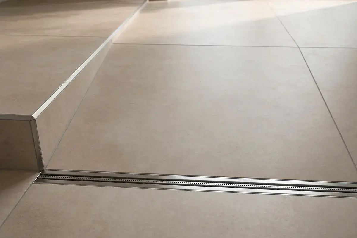 Linear shower drain in a curbless entry with large porcelain tile sloping toward it