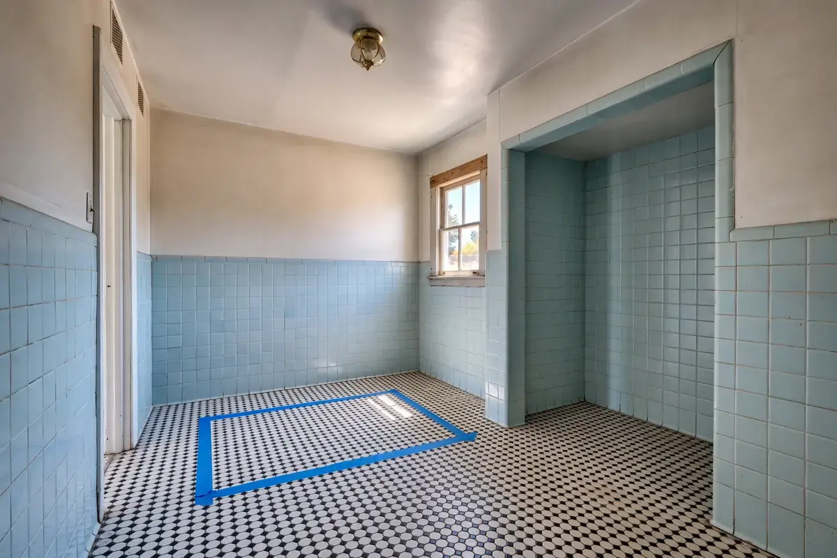 Empty small bathroom with painter's tape on the floor outlining a new layout