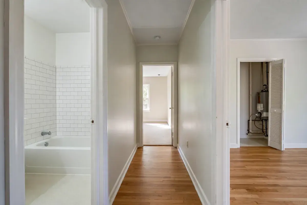 Narrow bathroom doorway looking toward an empty tub alcove, with a clear path from the hall